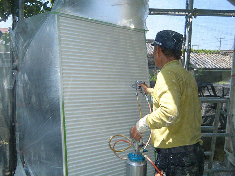 マンションのシャッターの吹き付け塗装を行う中年男性の塗装職人